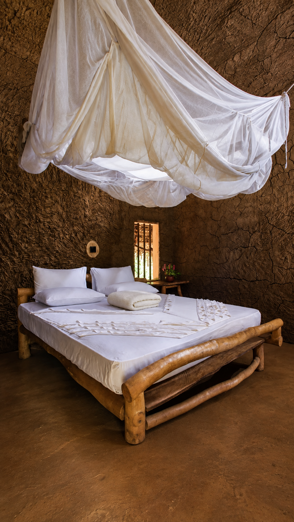 A serene earthen guest room with a canopy bed